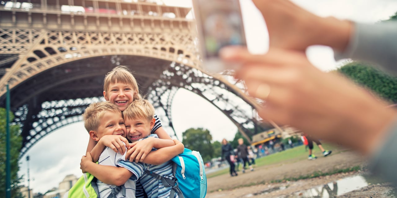 Three kids pose for a picture in front the Eiffel Tower in Paris
