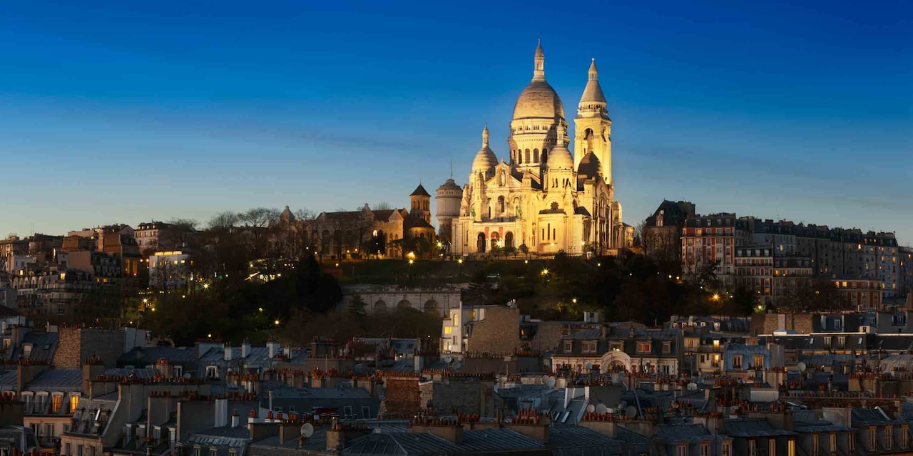 The Basilica of the Sacré Cœur is lit up high on Montmartre at dusk
