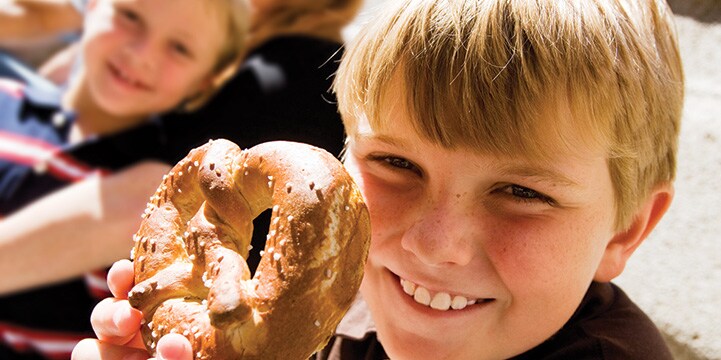 A smiling boy holds a large pretzel