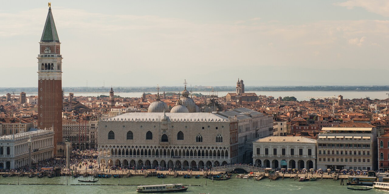 The city of Venice, Italy, including Doge’s Palace and the spired St. Mark’s Campanile, along a body of water 