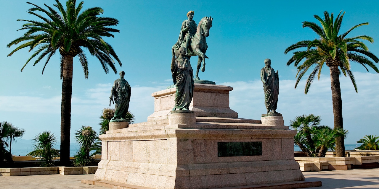 The statue of Napoleon Bonaparte on horseback and his 4 brothers stands between 2 palm trees The statue of Napoleon Bonaparte on horseback and his 4 brothers stands between 2 palm trees