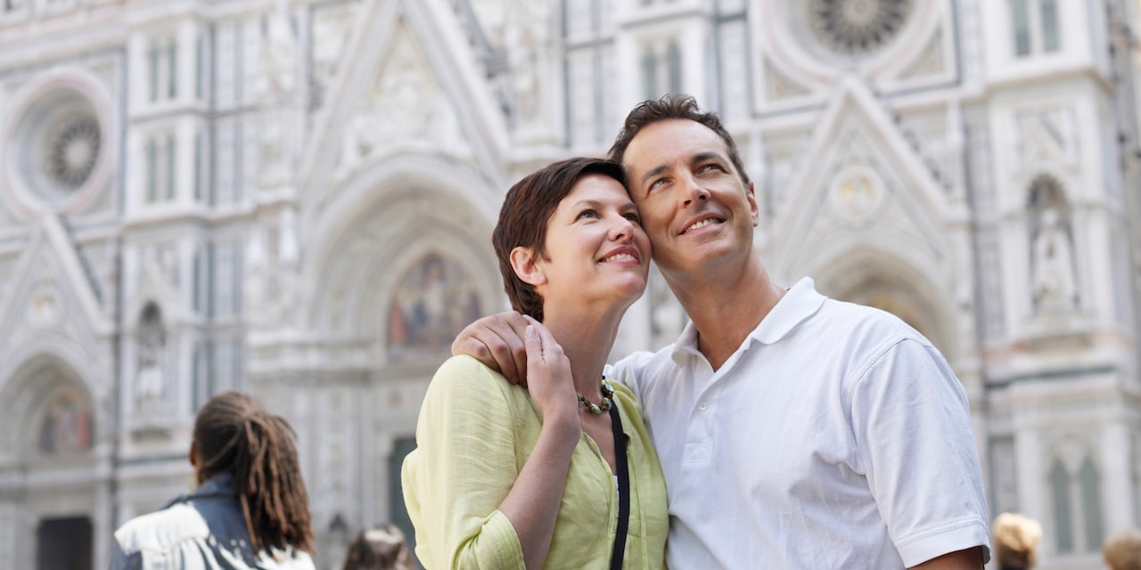 A couple admires the scenery as they sightsee near a cathedral A couple admires the scenery as they sightsee near a cathedral