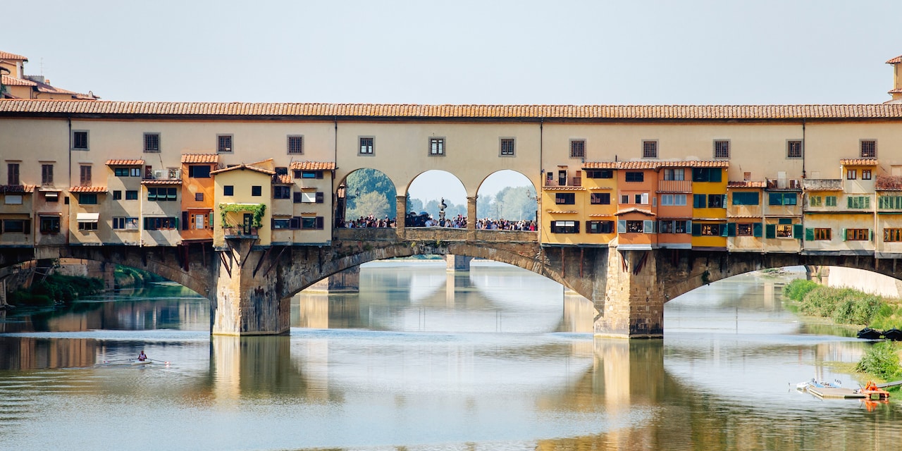 The shop-lined Ponte Vecchio bridge with stone arches spans the Arno River in Florence, Italy The shop-lined Ponte Vecchio bridge with stone arches spans the Arno River in Florence, Italy