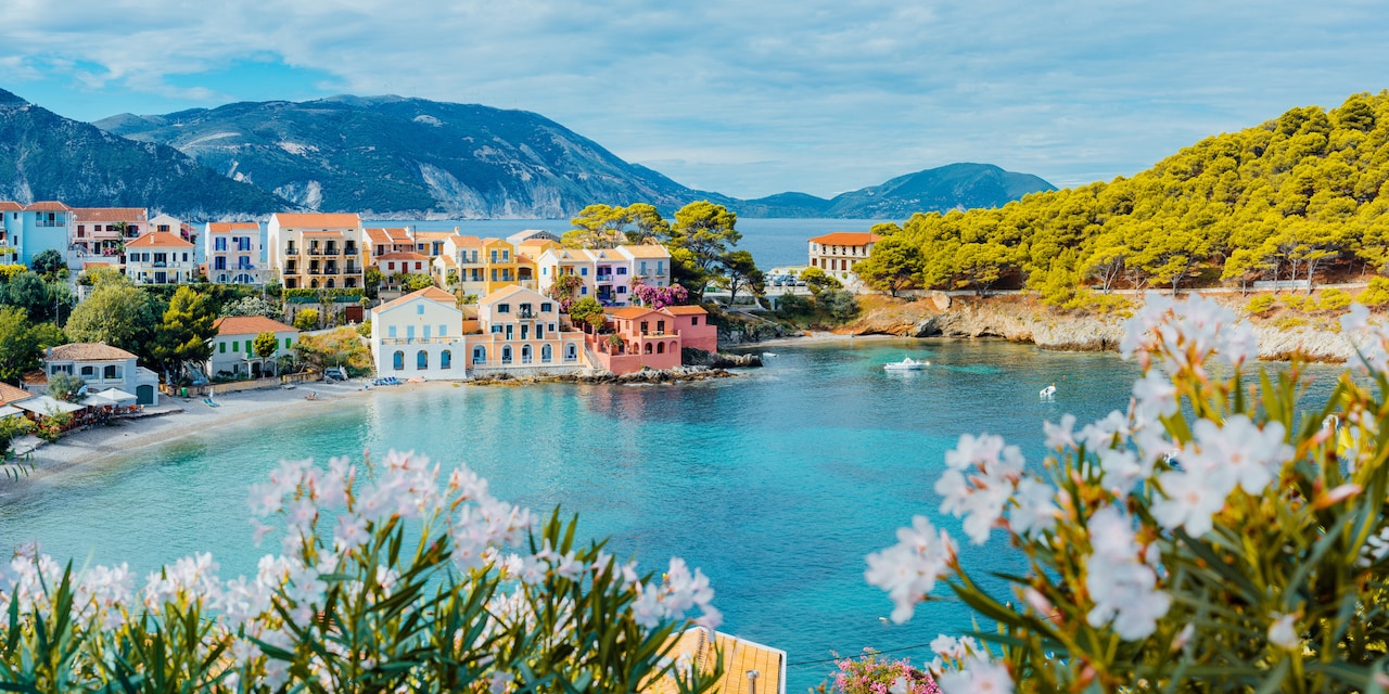 Colorful buildings along the shore of a bay in Kefalonia, Greece with mountains and a sea in the background Colorful buildings along the shore of a bay in Kefalonia, Greece with mountains and a sea in the background