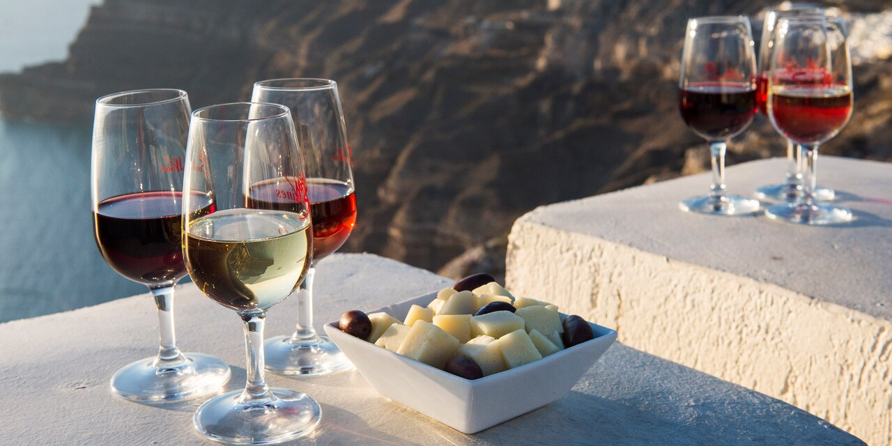 Six glasses of wine and a dish of cheese and olives sit on a ledge overlooking mountains near the sea Six glasses of wine and a dish of cheese and olives sit on a ledge overlooking mountains near the sea