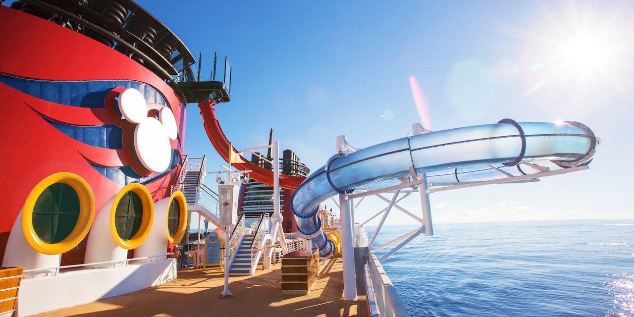 The top deck of the Disney Magic cruise ship with the AquaDunk water slide extending over the ocean and the Mickey Mouse logo on the ship’s Forward Funnel The top deck of the Disney Magic cruise ship with the AquaDunk water slide extending over the ocean and the Mickey Mouse logo on the ship’s Forward Funnel