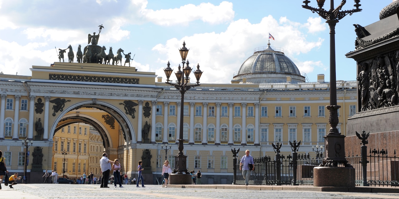 People walk in a courtyard near an archway with a statue on top and a domed building at the Hermitage Museum in St. Petersburg, Russia People walk in a courtyard near an archway with a statue on top and a domed building at the Hermitage Museum in St. Petersburg, Russia