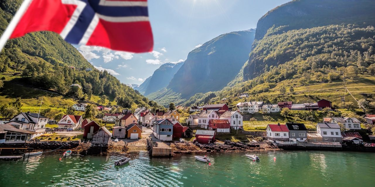 Houses line a quiet bay with a Norwegian flag visible