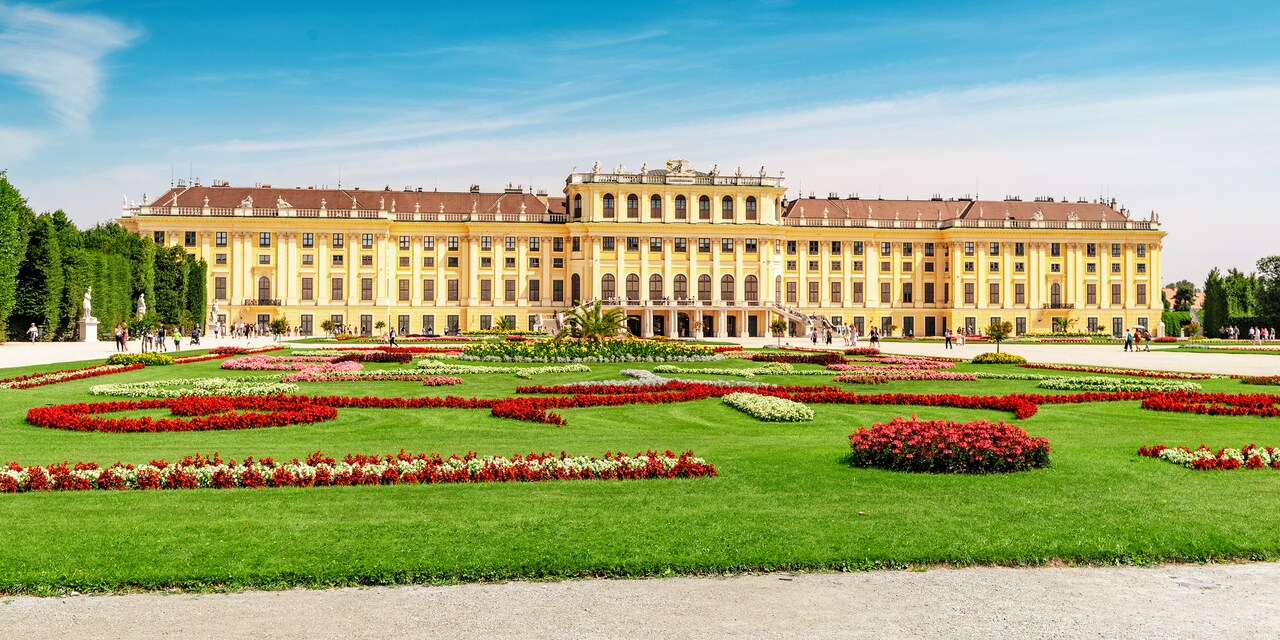 A lawn with flowers in front of a large palace