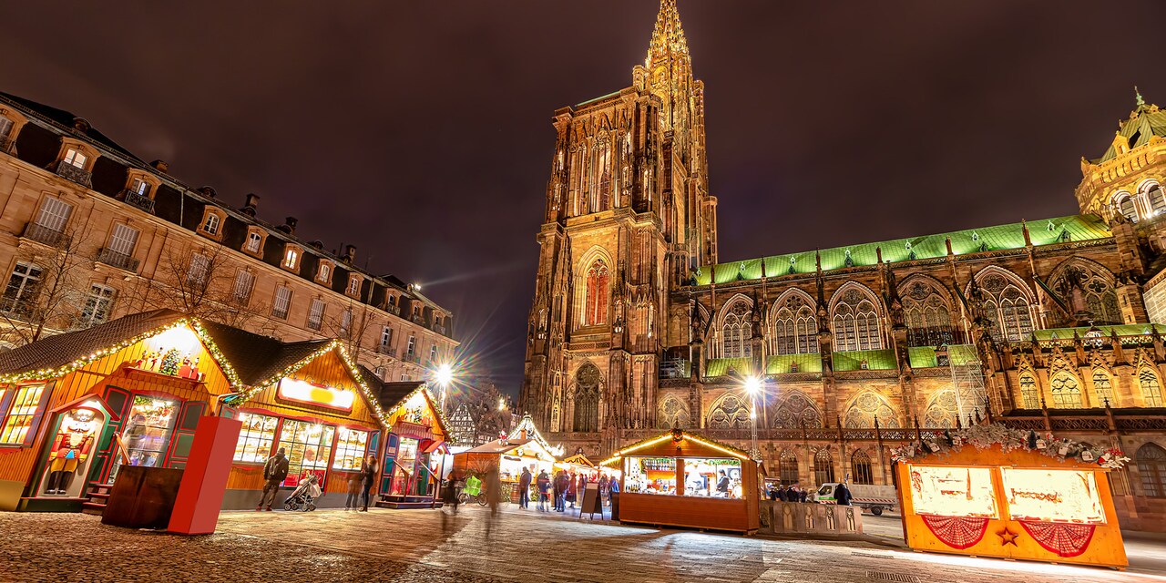 Christmas market stalls in the courtyard of a church in Strasbourg, France lit up at night