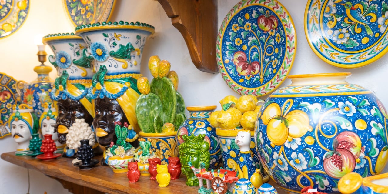 An assortment of decorative ceramic plates, figures, vases and lamp bases on a shelf and wall 