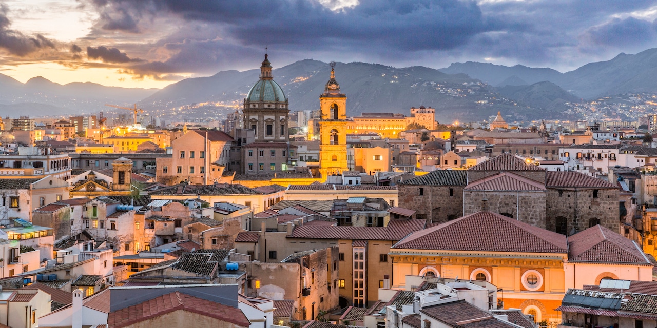 A large domed church dominates the skyline of Palermo, Italy at dusk