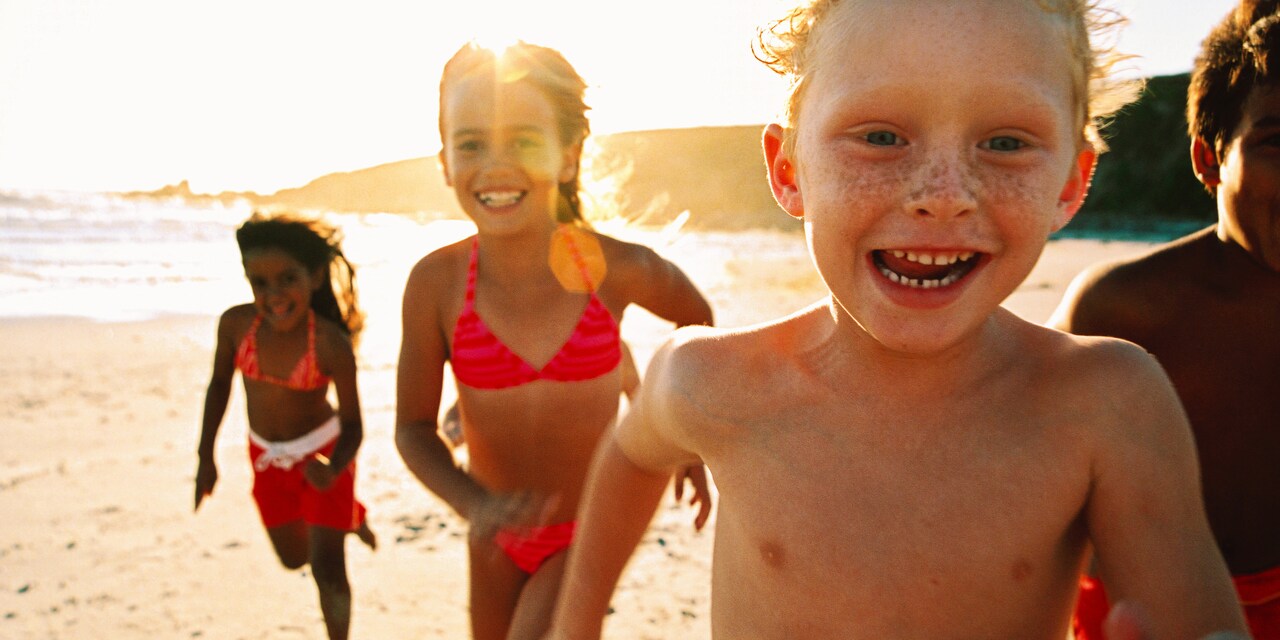 Several kids run along a sunny beach Several kids run along a sunny beach