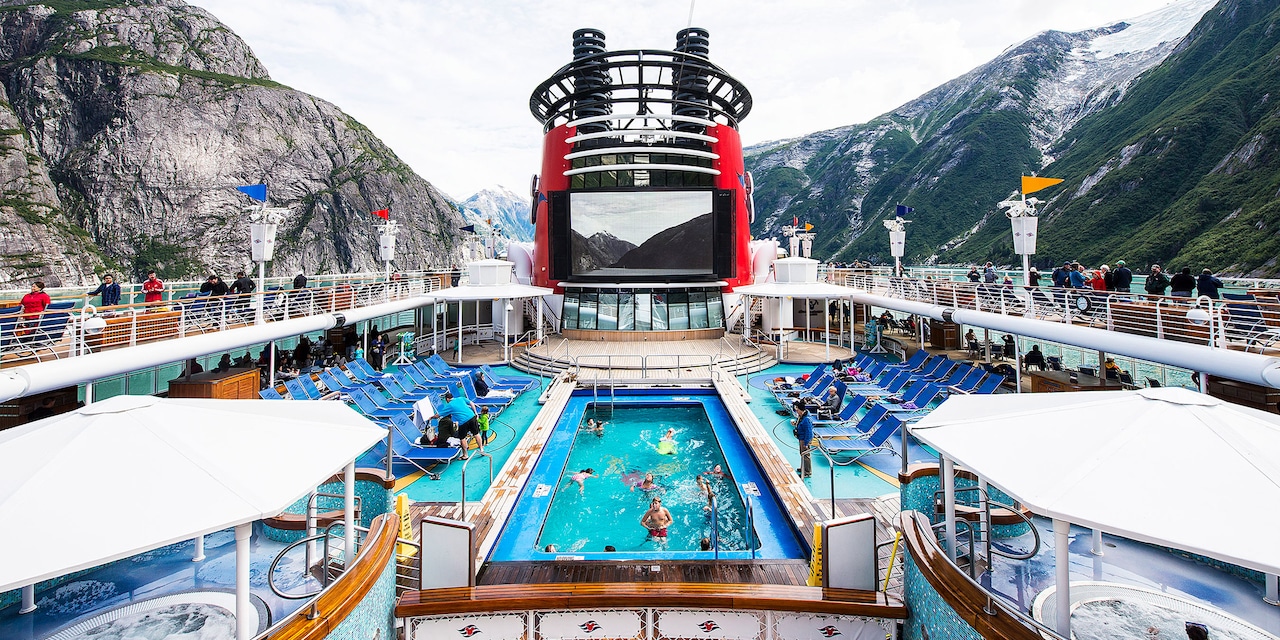 The pool and top deck area of the Disney Wonder cruise ship as it passes through a stretch of mountains The pool and top deck area of the Disney Wonder cruise ship as it passes through a stretch of mountains