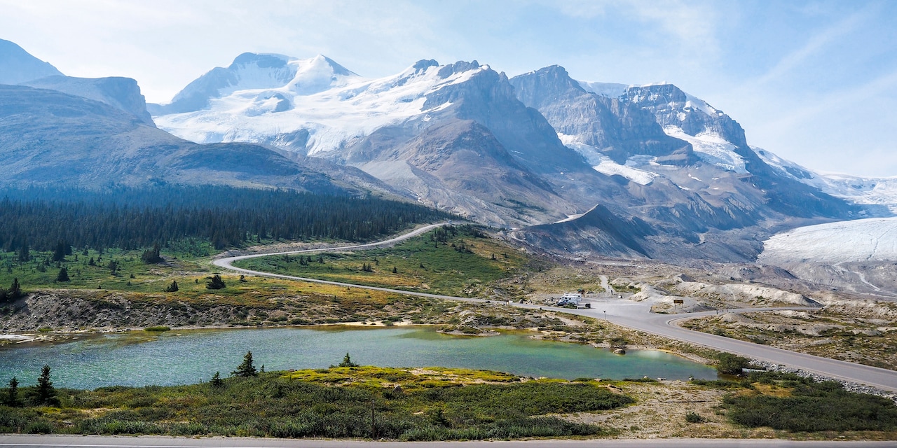 The snow-capped Canadian Rockies loom over the Columbia Icefield and a nearby valley with a lake