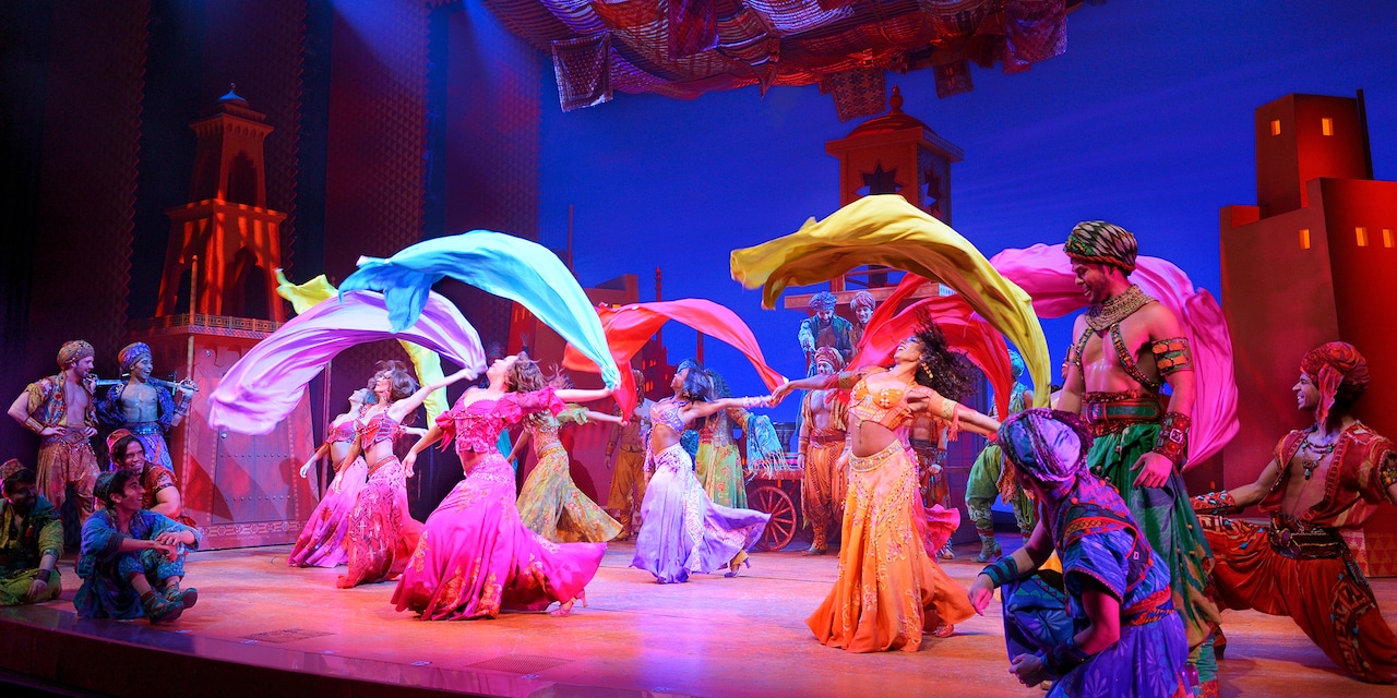 Cast Members dance on stage with scarves in Disney’s Aladdin: The Hit Broadway Musical Cast Members dance on stage with scarves in Disney’s Aladdin: The Hit Broadway Musical
