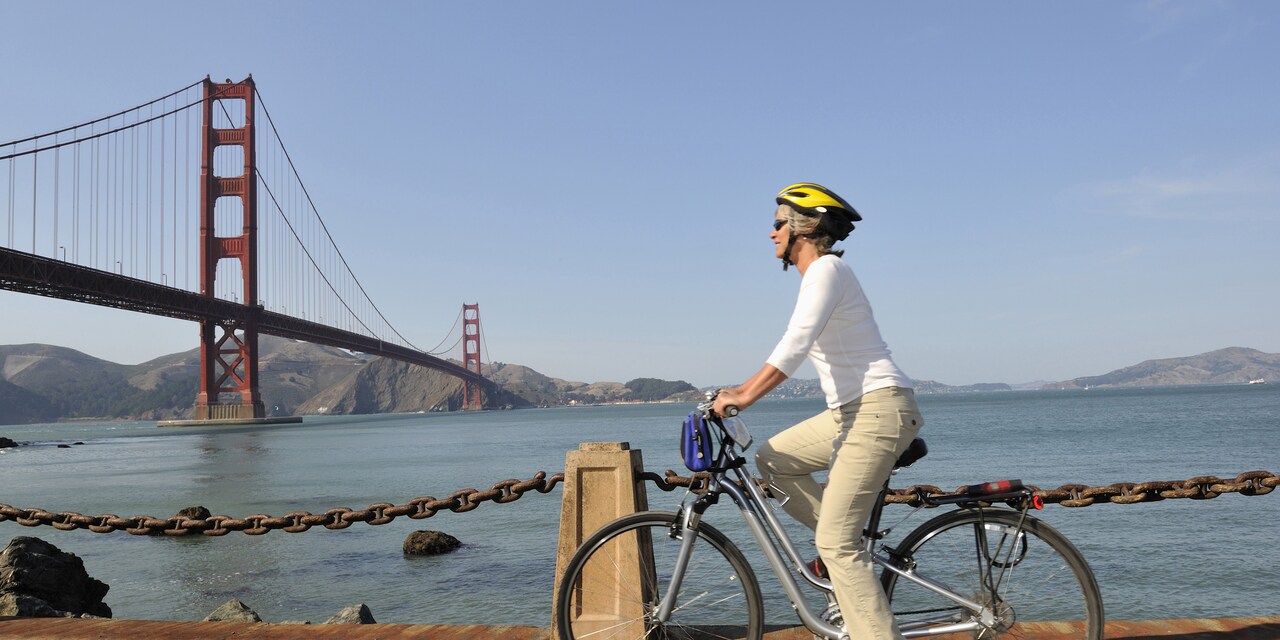 A woman rides a bike alongside San Francisco Bay near the Golden Gate Bridge A woman rides a bike alongside San Francisco Bay near the Golden Gate Bridge