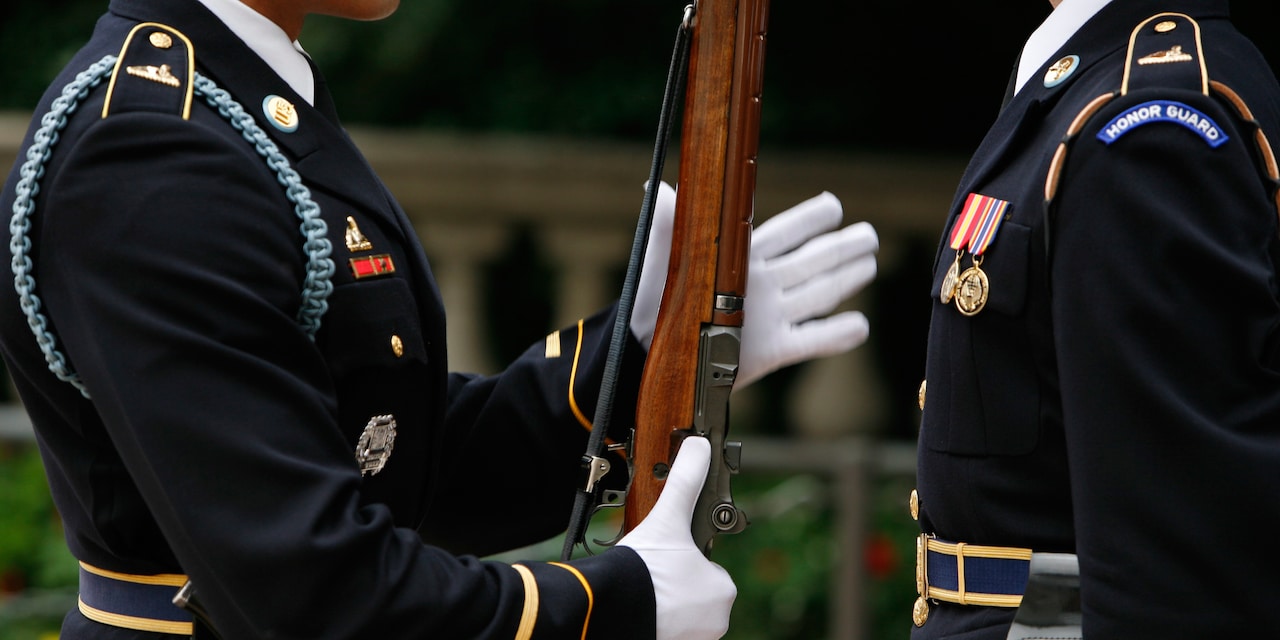 Two Honor Guards at the Arlington National Cemetery, with one holding a rifle as he presents arms Two Honor Guards at the Arlington National Cemetery, with one holding a rifle as he presents arms