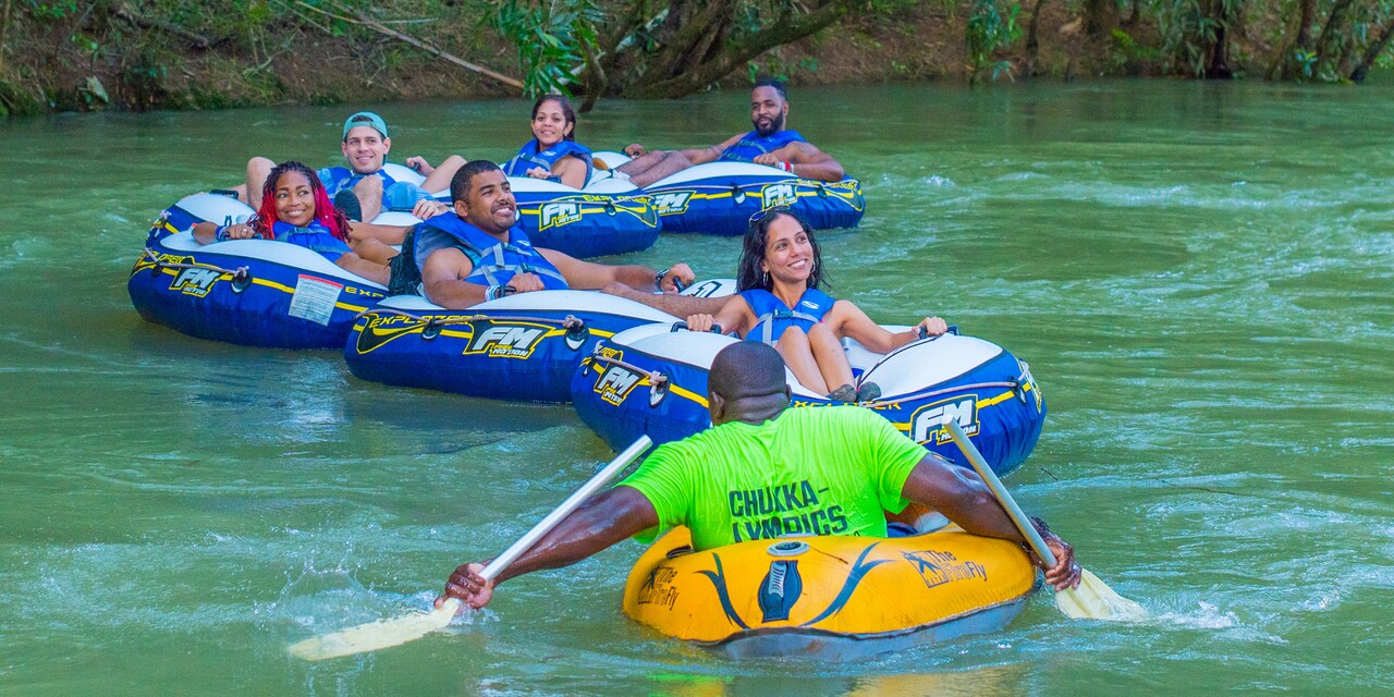 A guide faces a group of people on inner tubes he leads down a river A guide faces a group of people on inner tubes he leads down a river