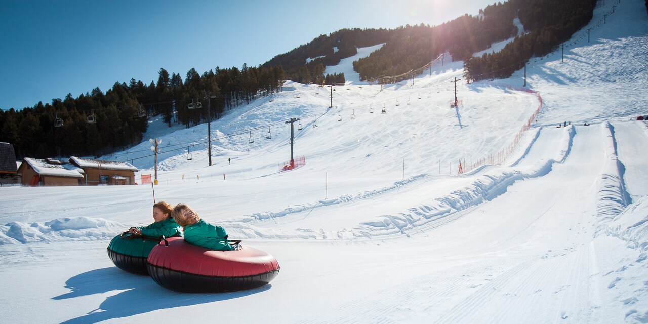 Two girls ride inner-tubes down a snowy track at Snow King Mountain in Jackson, Wyoming