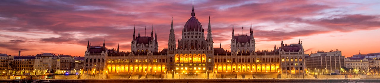 The Budapest Parliament building at sunset, with reflections of its lights on the Danube River