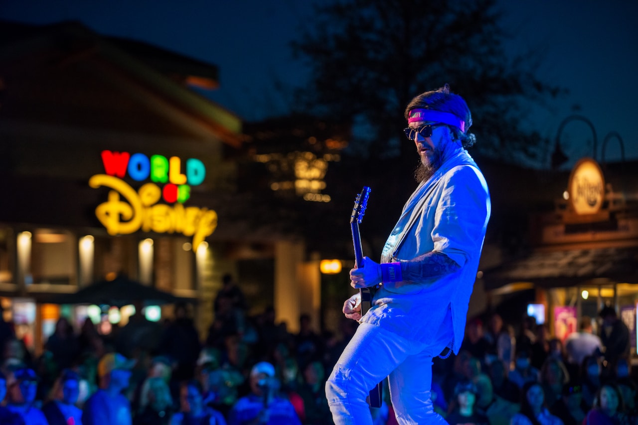 A musician playing guitar on the Advent Health Waterside Stage at Disney Springs