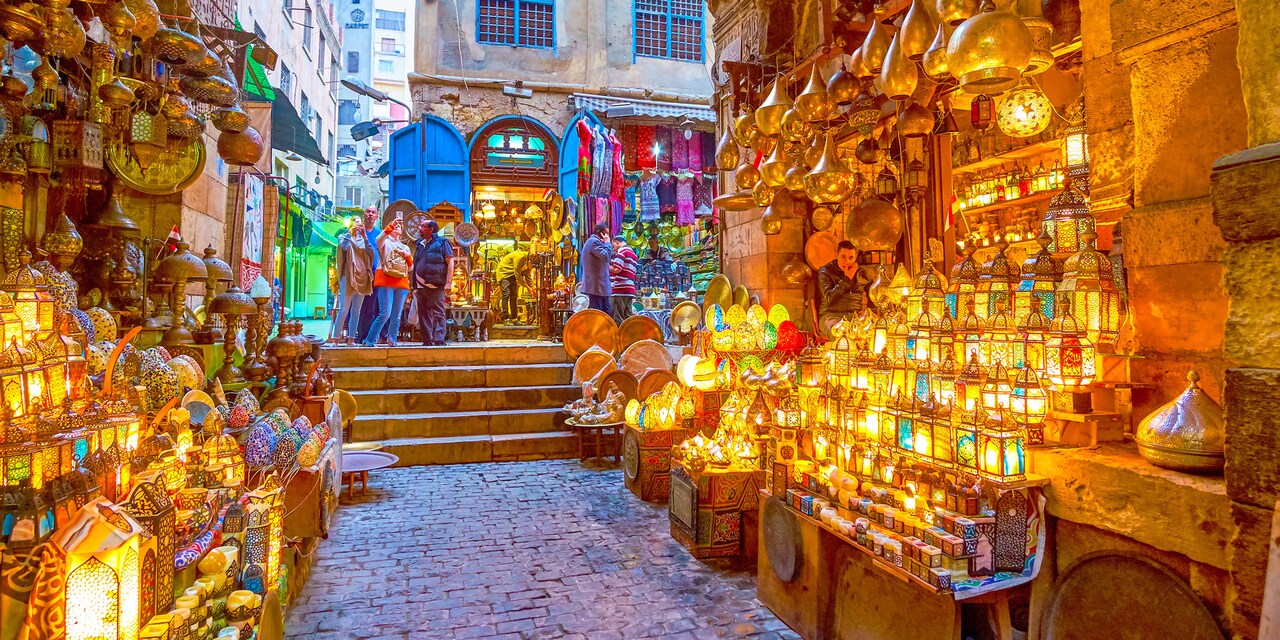 A group of tourists explore a marketplace featuring large displays of illuminated lanterns