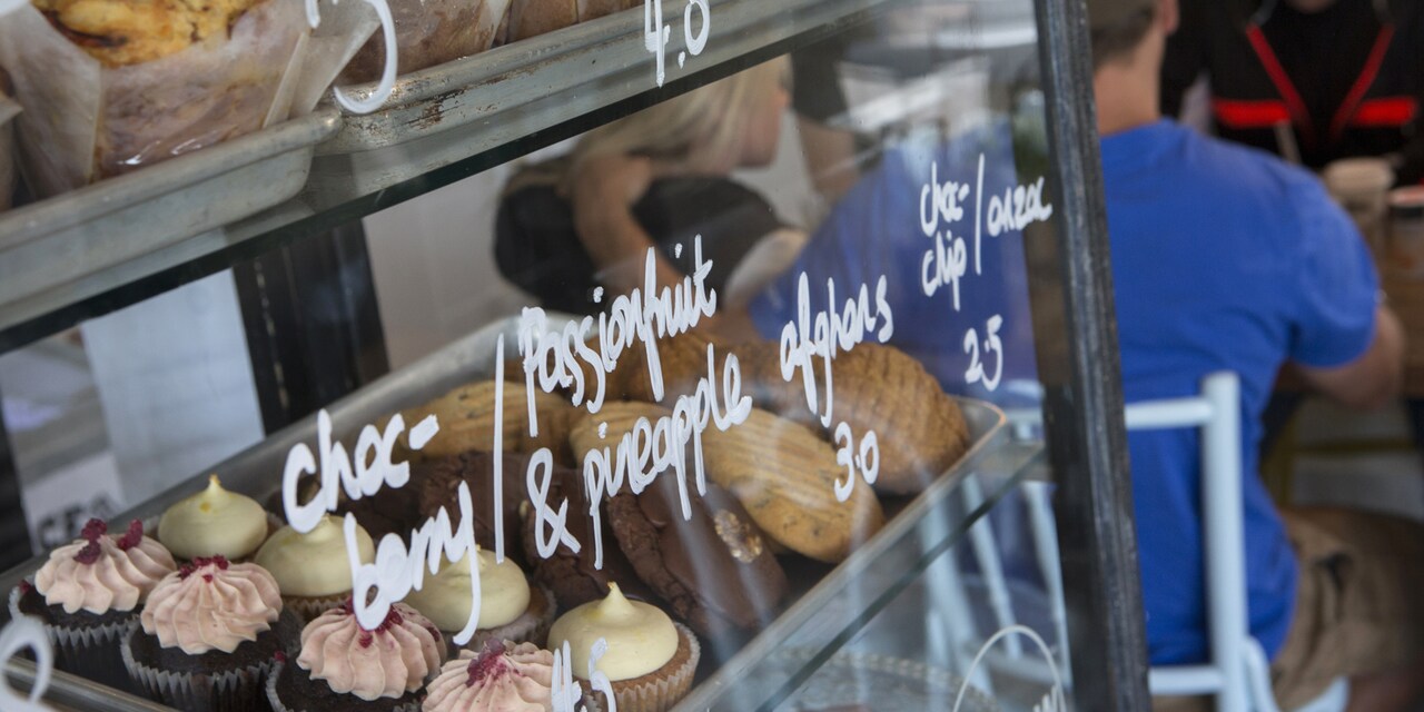 Shelves filled with an assortment of pastries in a glass case with the prices written on the glass