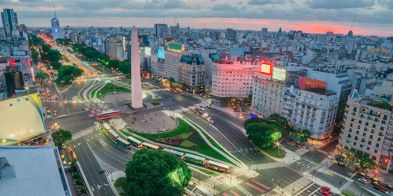 An aerial image of the city of Buenos Aires at dusk with the Obelisco in the middle of a large intersection