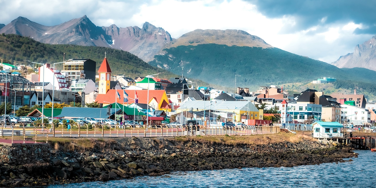 Seaside town of Ushuaia with buildings and flags at the base of the Andes Mountain Range