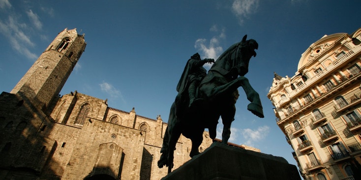 A monument of a king riding his horse surrounded by buildings