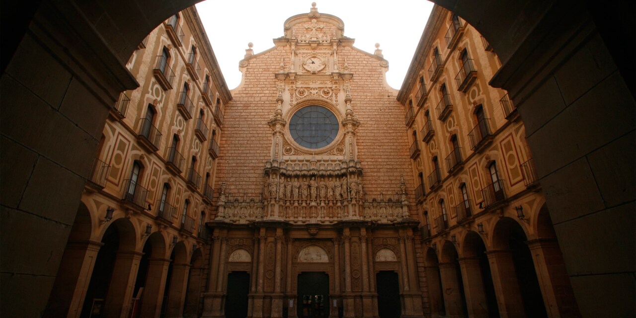 A view of the Santa Maria de Montserrat Abbey façade with its clock, round window and statues of the disciples