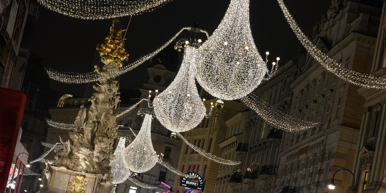 Hanging holiday lights span across a Vienna street with an ornate fountain