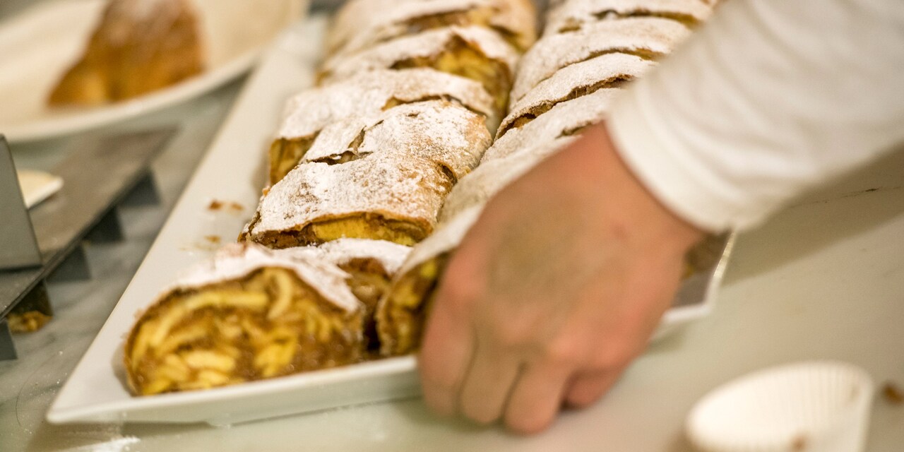 A person picks up a tray filled with rows of strudel
