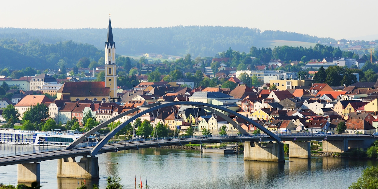 A bridge over a river and a quaint town with a steepled church on one side
