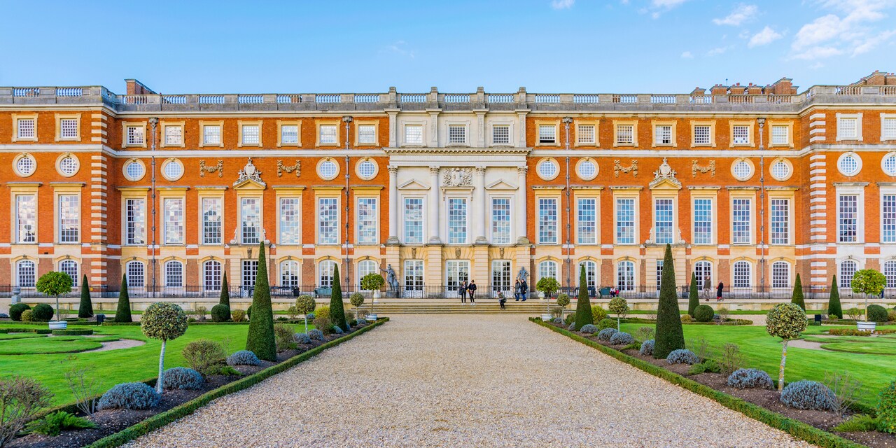 A gravel path cuts through a garden leading to the exterior of Hampton Court Palace 