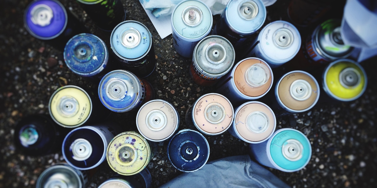 A birds-eye view of a variety of uncapped spray paint cans