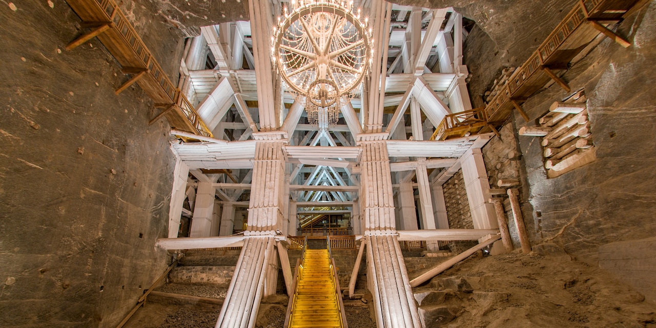 A chandelier hangs from the ceiling amid the interior structures within the Wieliczka Salt Mine
