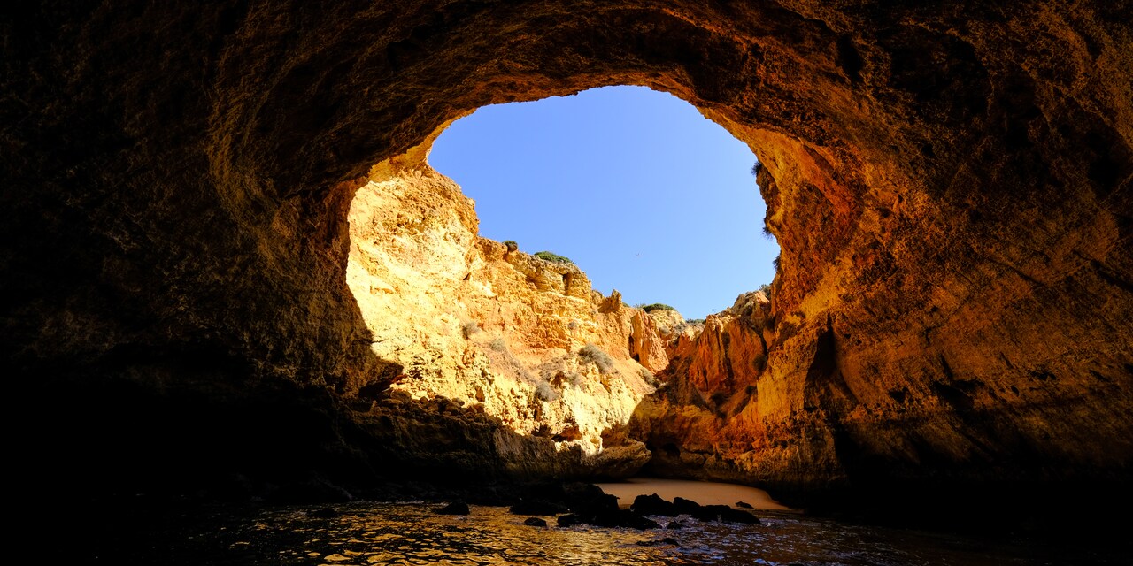 A view of the sky from inside a cave at a beach