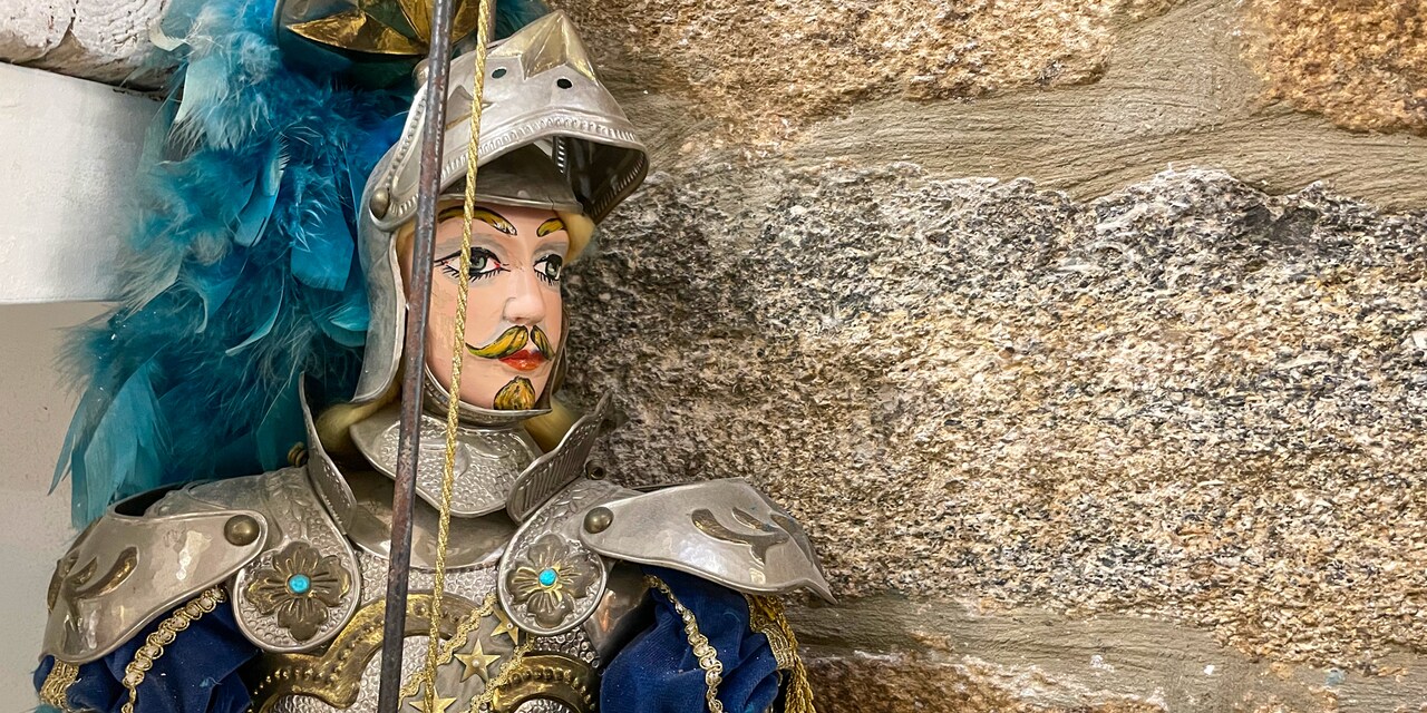 A knight in armor puppet against a stone wall