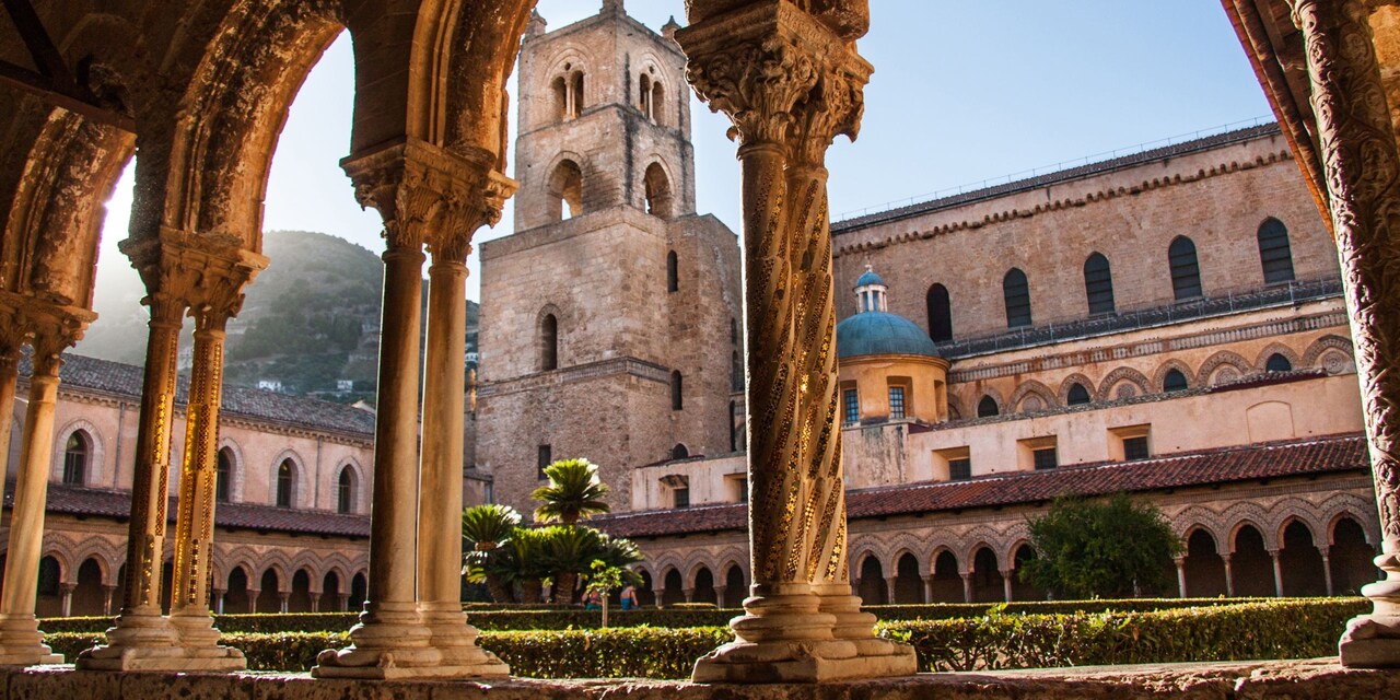 A courtyard in the Monreale Cathedral and Monastery with columns and domed building