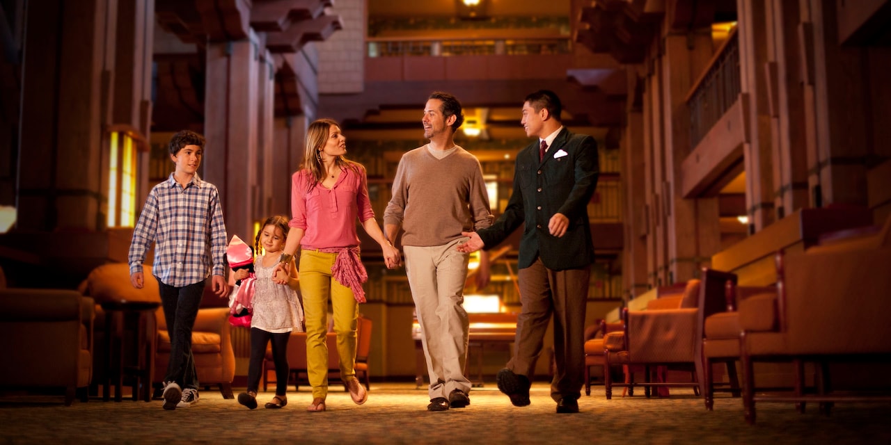 A male Cast Member leads a family of 4 through the lobby of Disney’s Grand Californian Hotel & Spa at Disneyland Resort