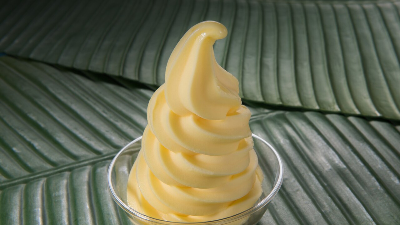 Postre de helado suave de piña en un tazón transparente sobre hojas de plátano