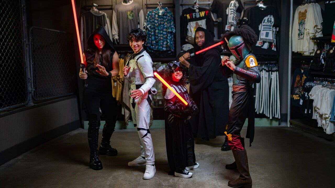 A group of kids pose with lightsabers at Star Wars Trading Post in Disney Springs 