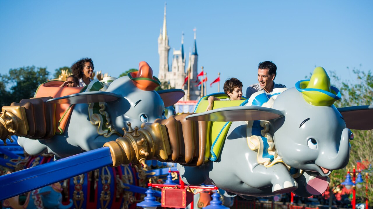 Guests smiling as they ride Dumbo the Flying Elephant at Magic Kingdom park