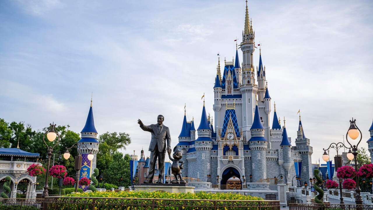 A statue of Walt Disney and Mickey Mouse in front of Cinderella Castle