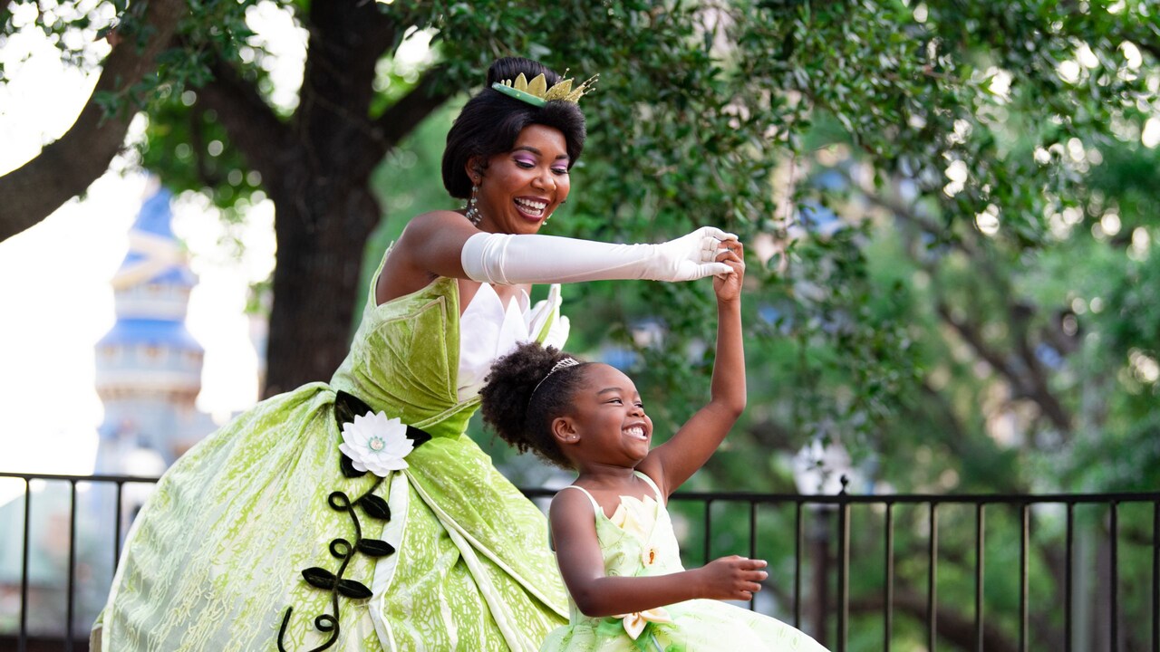 Tiana dances with a little girl wearing a Tiana dress