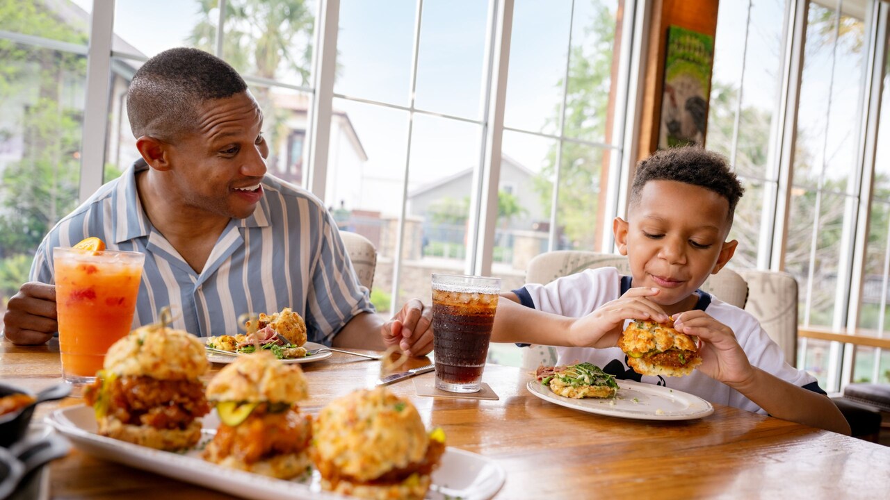 An adult and child eating chicken biscuits together at a table at Chef Art Smith's Homecomin'