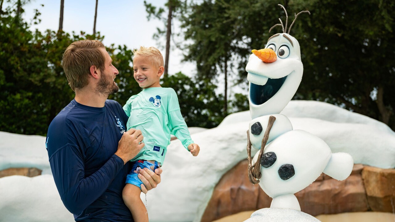 A father and son near the animatronic of Olaf during Holidays at Walt Disney World Resort