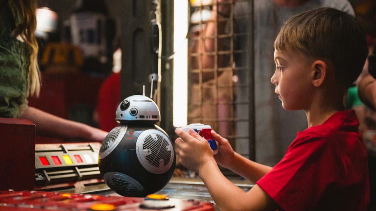 A boy interacting with a BB series droid inside the Droid Depot at Star Wars, Galaxy’s Edge